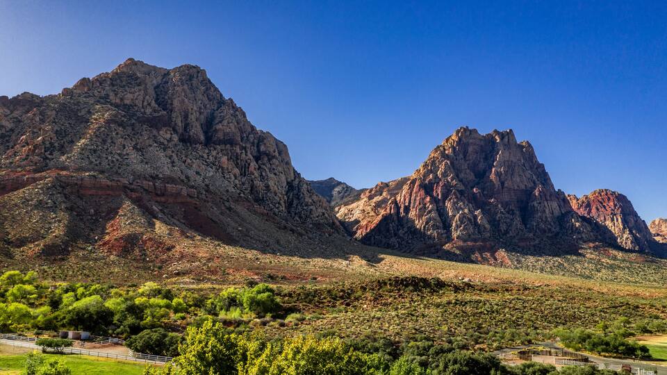 A mountainous landscape with prominent rocky peaks and a foreground of green vegetation.