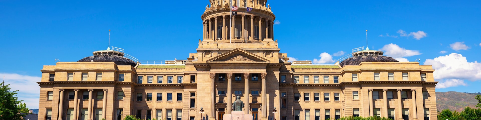 A large, neoclassical building with a prominent dome and columns, surrounded by well-maintained lawns and bushes.