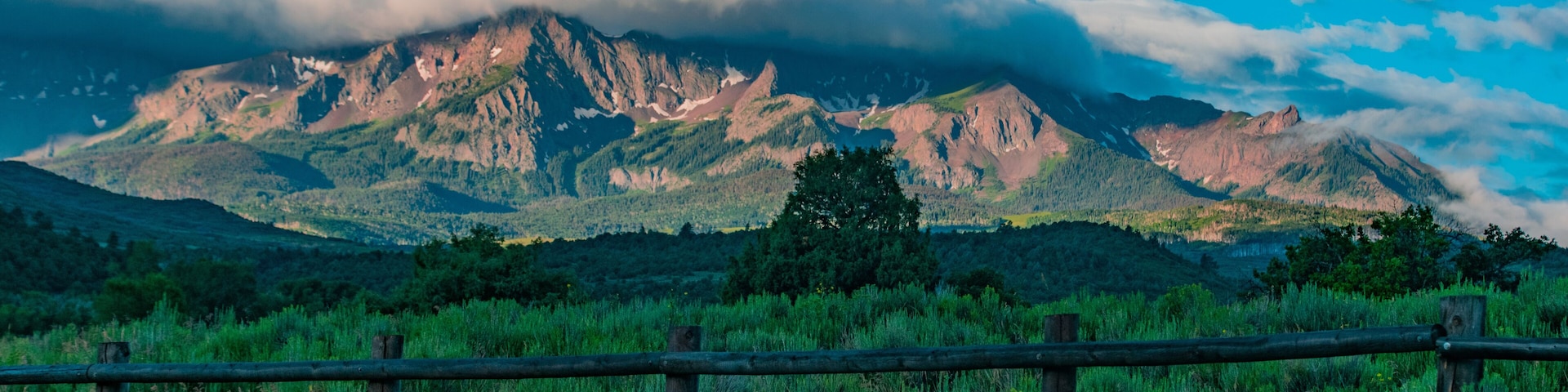A mountainous landscape with a wooden fence in the foreground.