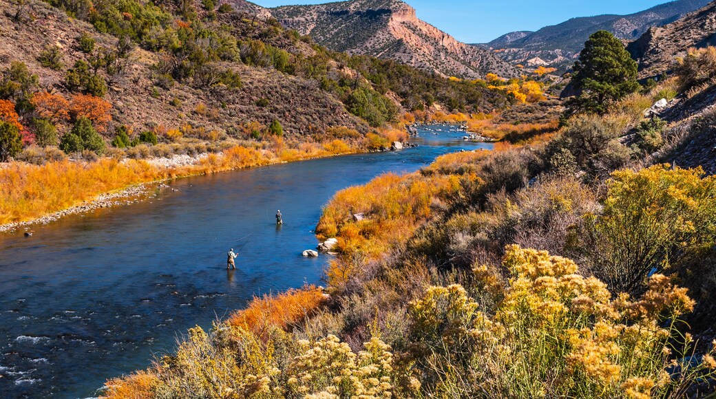 A river flowing through a mountainous landscape with autumn-colored trees.