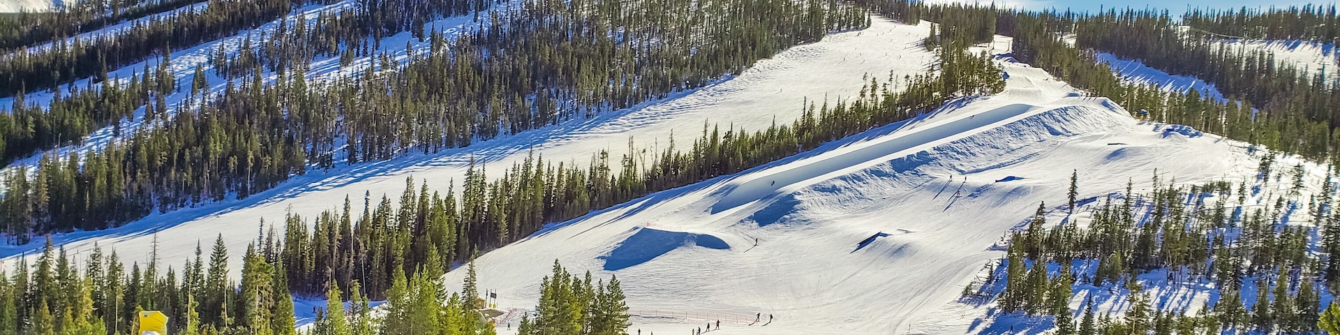 View of ski slope with terrain park and woods in Colorado ski resort  on nice winter day; blue sky in background