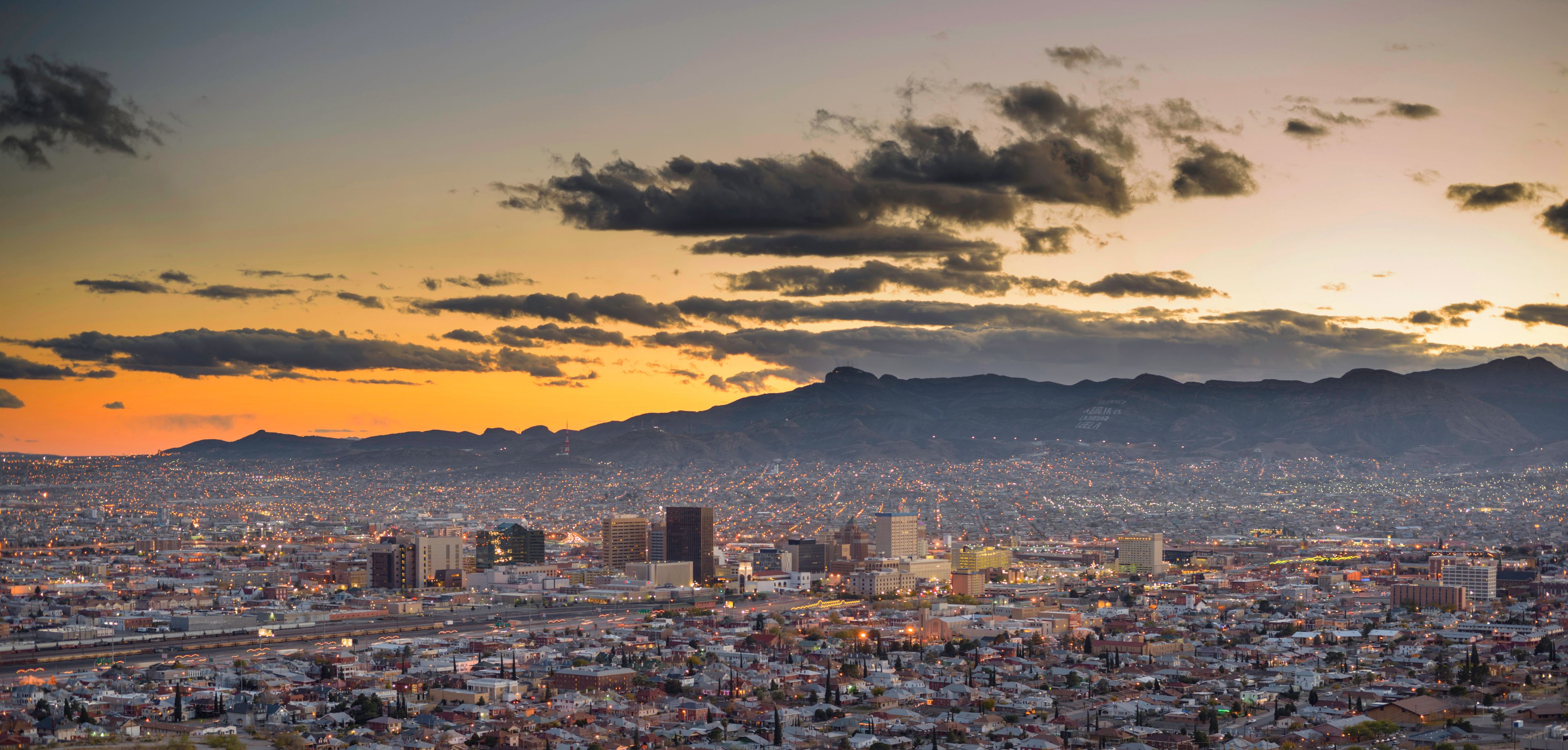 A cityscape at dusk with a mountain range in the background.