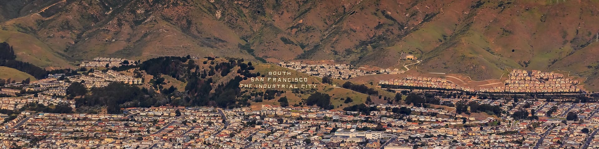 Aerial view of downtown San Francisco and Financial District sky scrapers flying over South San Francisco The Industrial City inscription on San Bruno mountain circa 2015