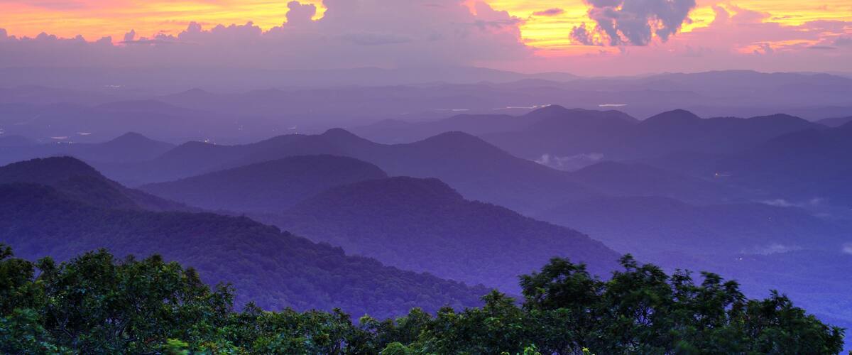 A mountainous landscape with a sunset sky.