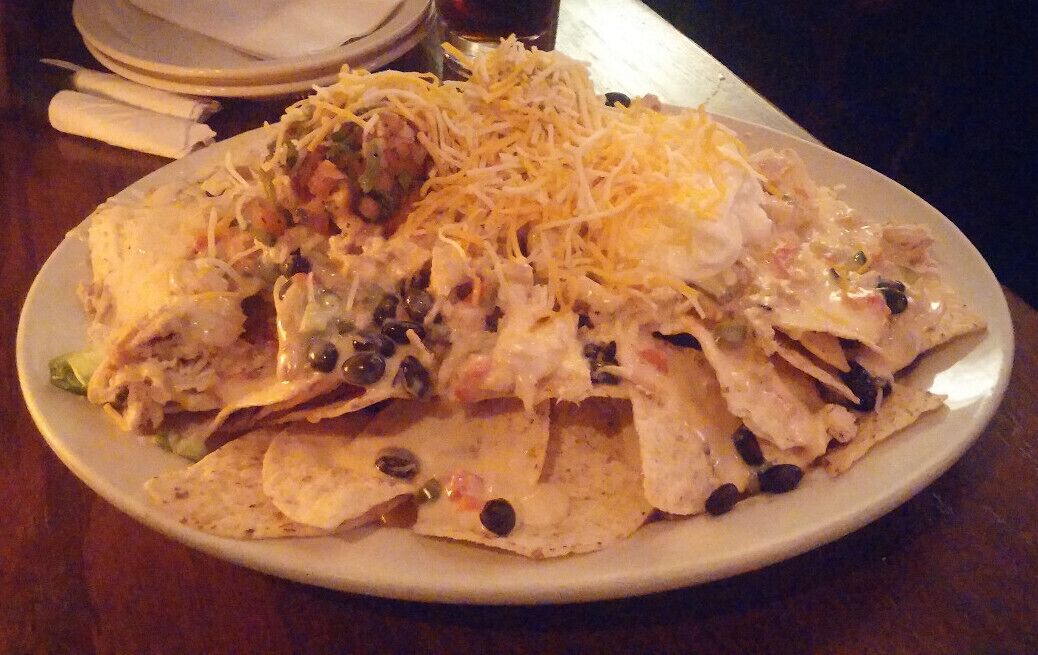 Tavern Nachos: An absolute mountain of tortilla chips topped with black beans, jalapeno, queso, house made guacamole, sour cream, pico de gallo and pulled chicken.