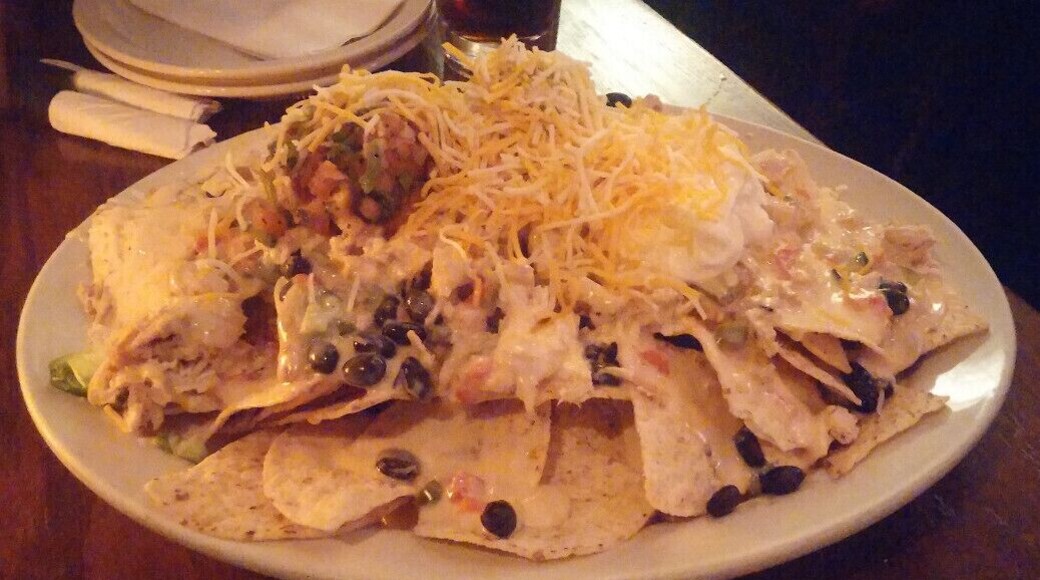 Tavern Nachos: An absolute mountain of tortilla chips topped with black beans, jalapeno, queso, house made guacamole, sour cream, pico de gallo and pulled chicken.