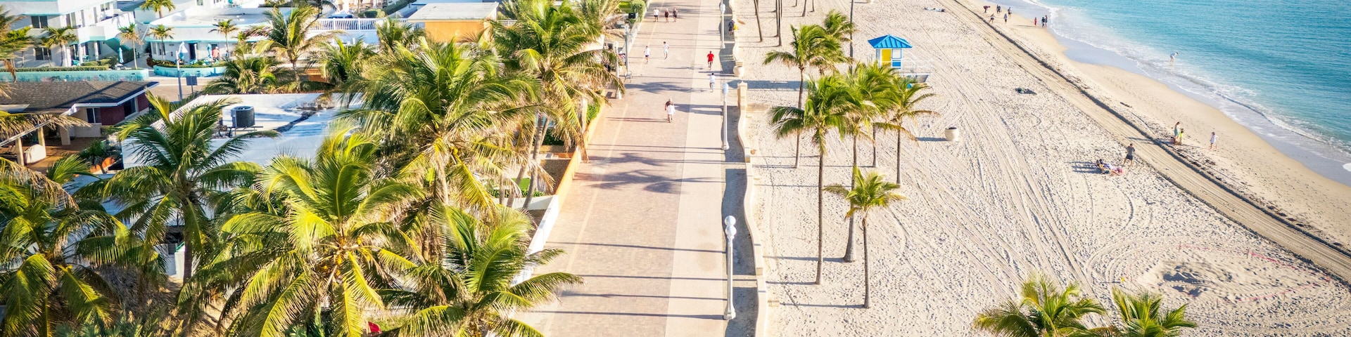 Uma praia com palmeiras, um hotel e um céu azul límpido.