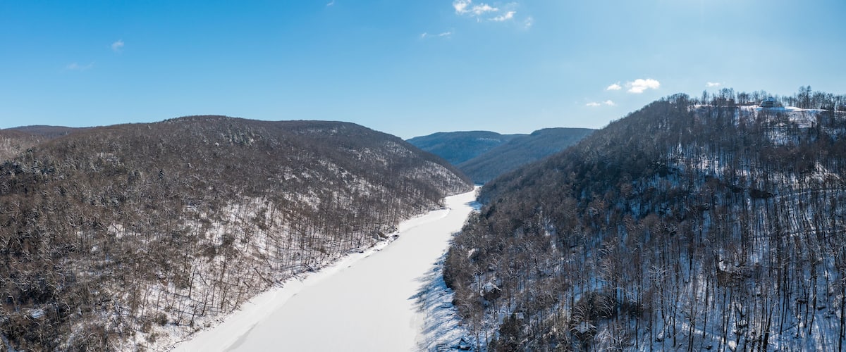 Aerial drone view of the snow-covered and frozen Cheat River flowing through the mountains towards the lake near Morgantown in West Virginia
