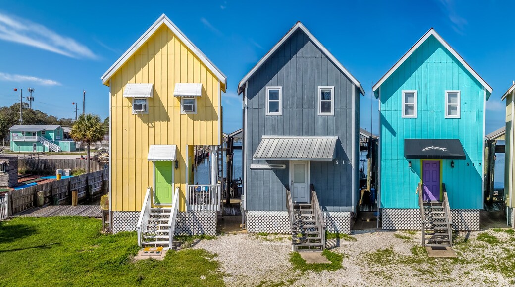 Colorful two story vacation homes with vivid yellow, blue, green, pink paint, wooden steps to door, boat parking structure in back on Dauphin island Alabama