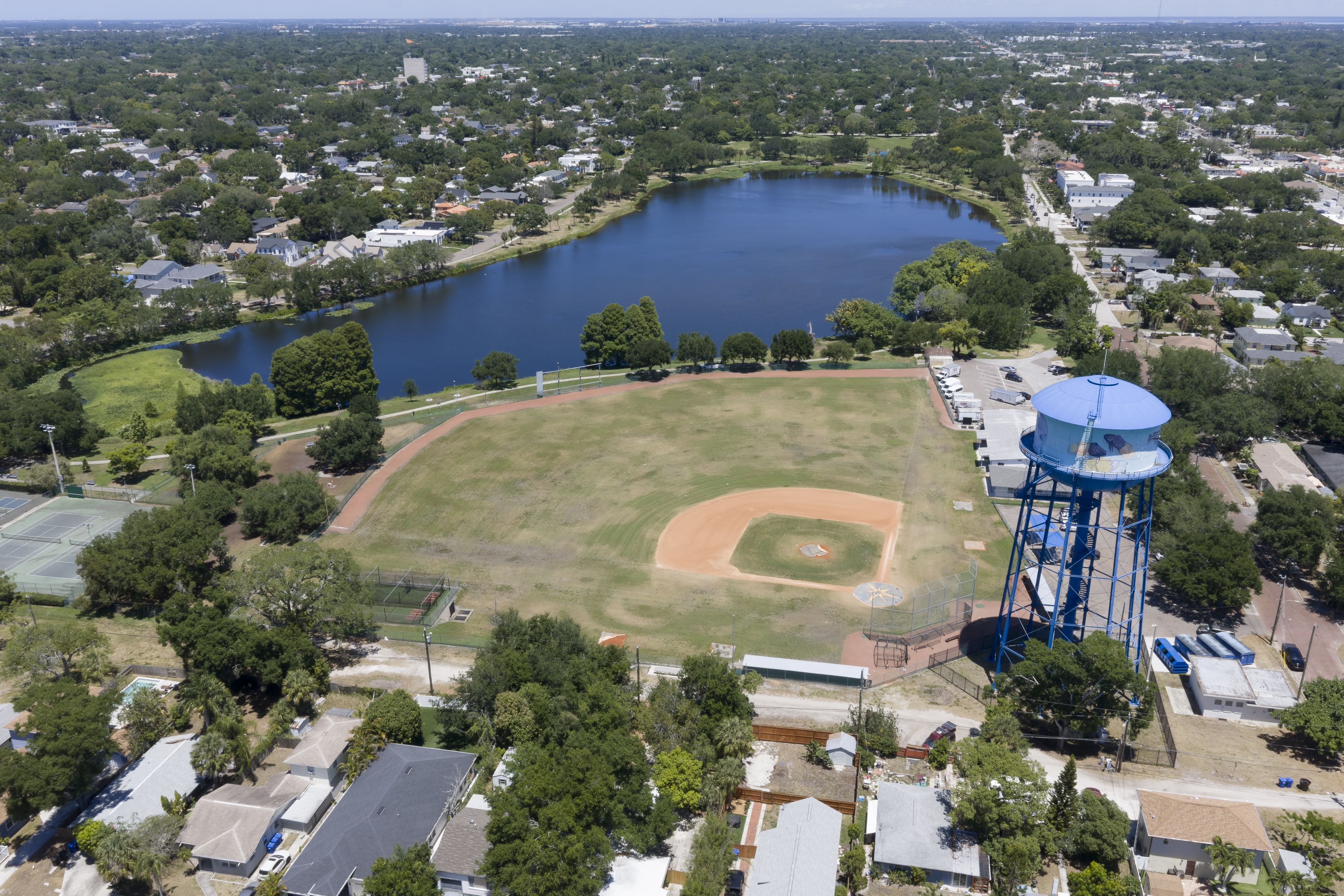 Aerial view of the St. Petersburg water tower overlooking a baseball field and a nearby lake surrounded by residential houses and lush green trees in St. Petersburg, Florida, United States.