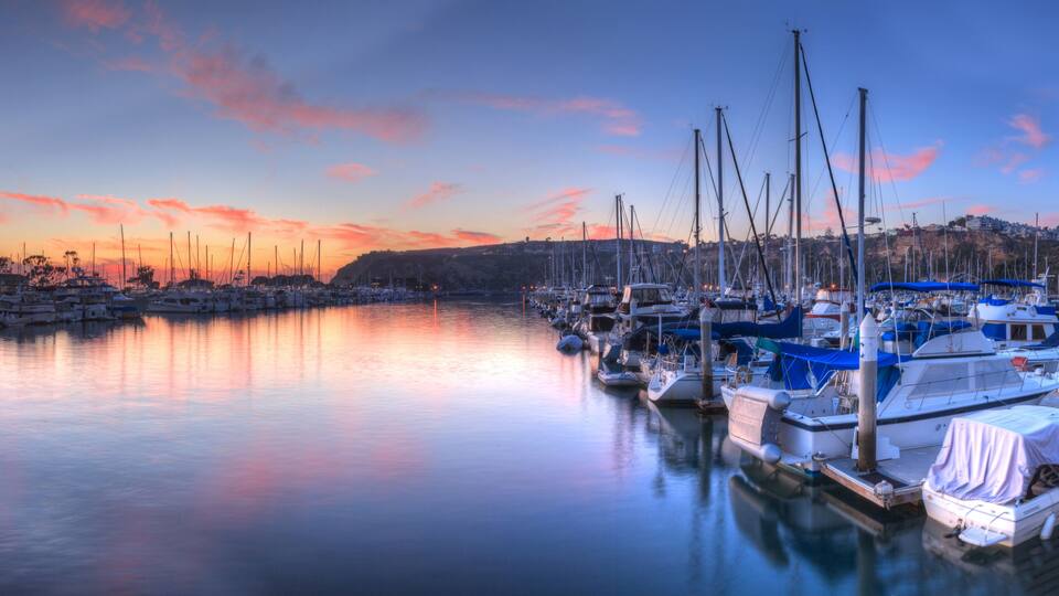 Sunset over sailboats in the calm water of the Dana Point harbor in Southern California, USA