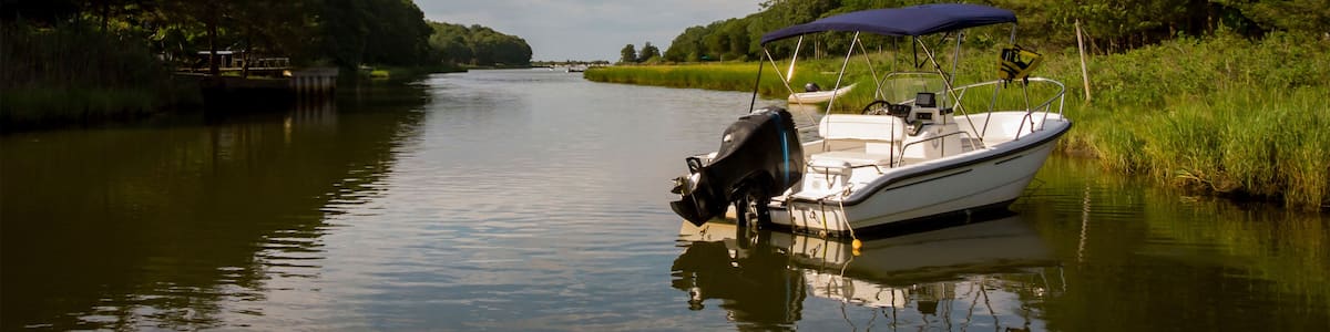 A calm river with a boat docked on the right bank, surrounded by lush greenery and trees.