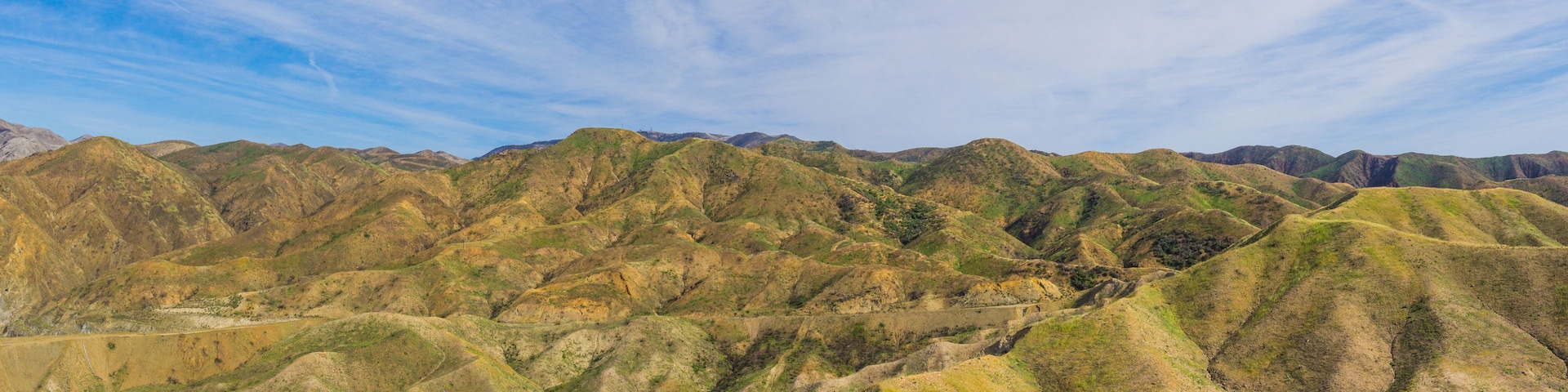 Eine gebirgige Landschaft mit sanften Hügeln und blauem Himmel.