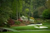 A golf course with sand bunkers, a stone bridge, and a variety of trees and flowering plants.