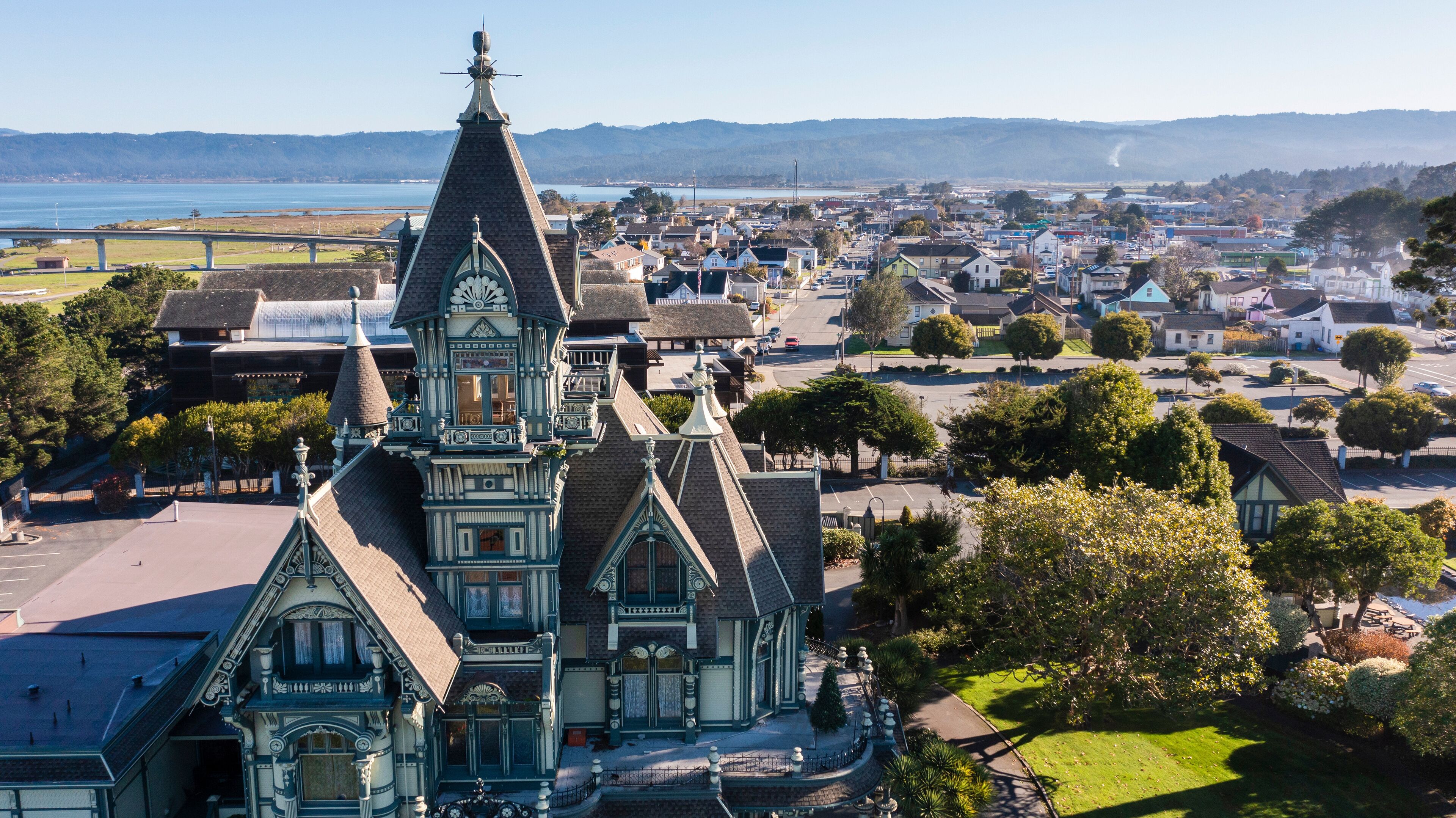 A historic church with intricate architecture, surrounded by a small town with houses and a view of the sea.