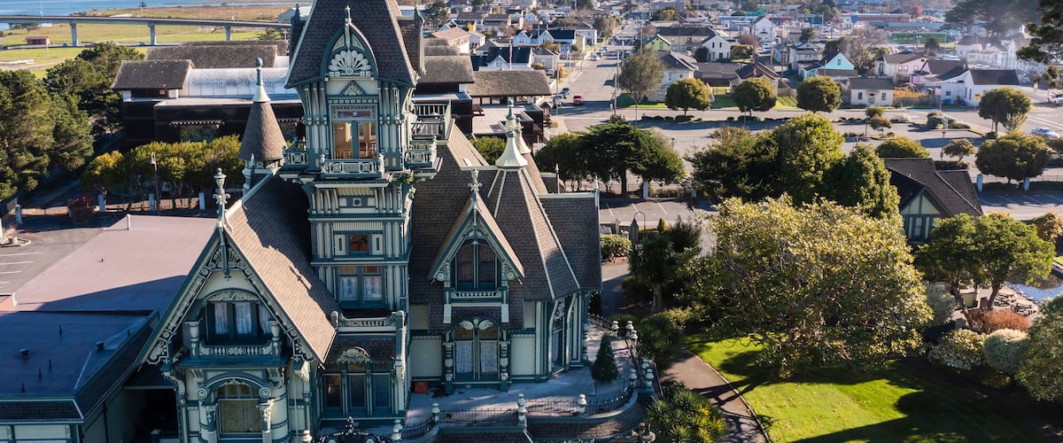 A historic church with intricate architecture, surrounded by a small town with houses and a view of the sea.