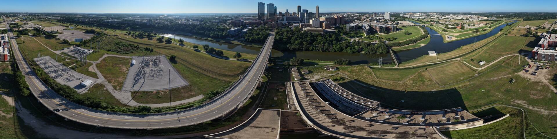 A cityscape with a river, green spaces, and a large stadium.
