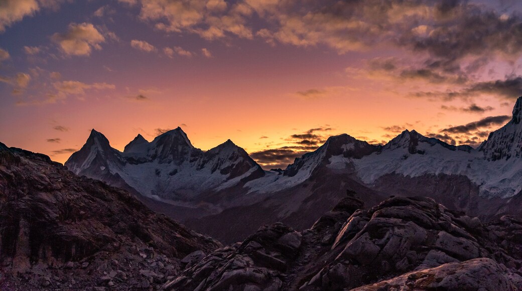 amazing sunset panorama over snowy mountain range with big glaciers with red, orange, violet and moonlight colors