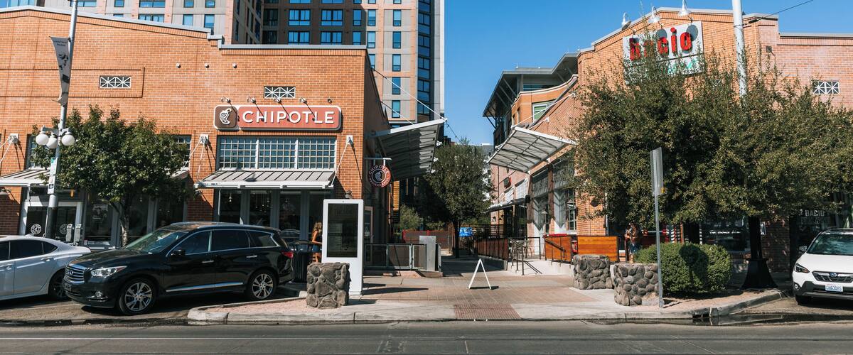 En Chipotle restaurant, en hvid bil og en bygning med et rødt skilt.