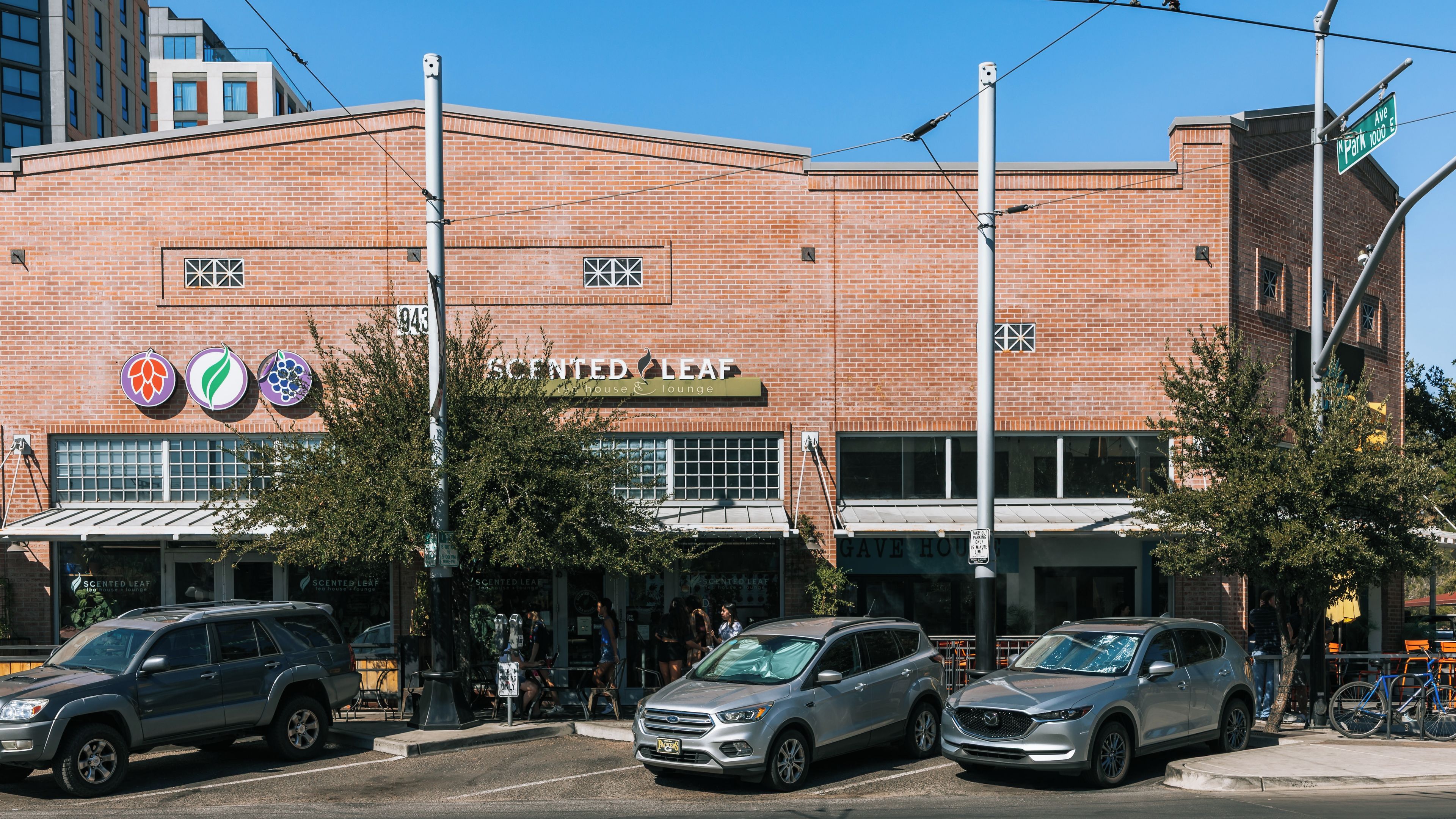 Un edificio de ladrillo con un letrero que dice 'Scented Leaf House & Lounge' y automóviles estacionados.