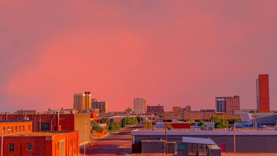 A brilliant sunset colors downtown Lubbock, Texas, including the streets and buildings.