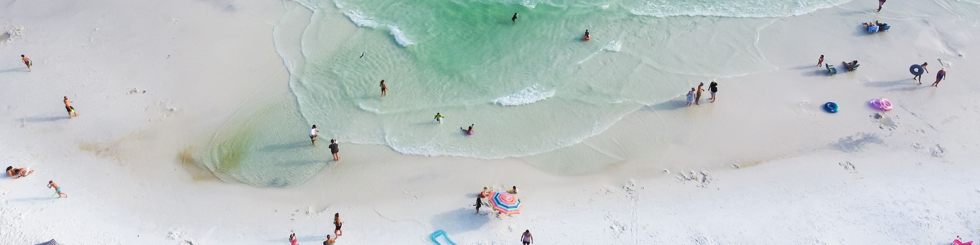 Gorgeous shade of blue and crystal-clear turquoise water of Santa Rosa beach, brilliantly white sandy shore with people swimming, relaxing laid-back vibe charming Walton County, Florida, USA