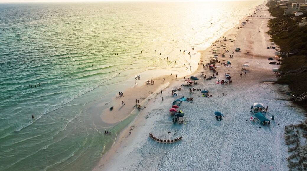 Sunset over Santa Rosa beach with colorful beach chairs, umbrellas and people swimming, relaxing laid-back along white sandy beaches, turquoise water, gorgeous shade of blue Florida, USA