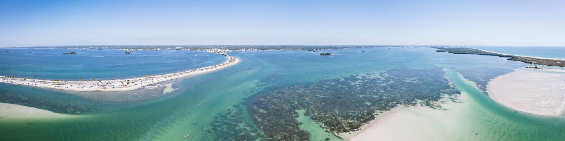 Aerial view of colorful boats navigating through Hurricane Pass and coral reef with sandy sandbanks, Dunedin, Florida, United States.
