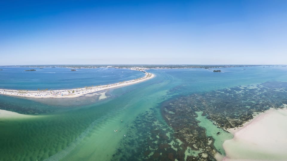 Aerial view of colorful boats navigating through Hurricane Pass and coral reef with sandy sandbanks, Dunedin, Florida, United States.