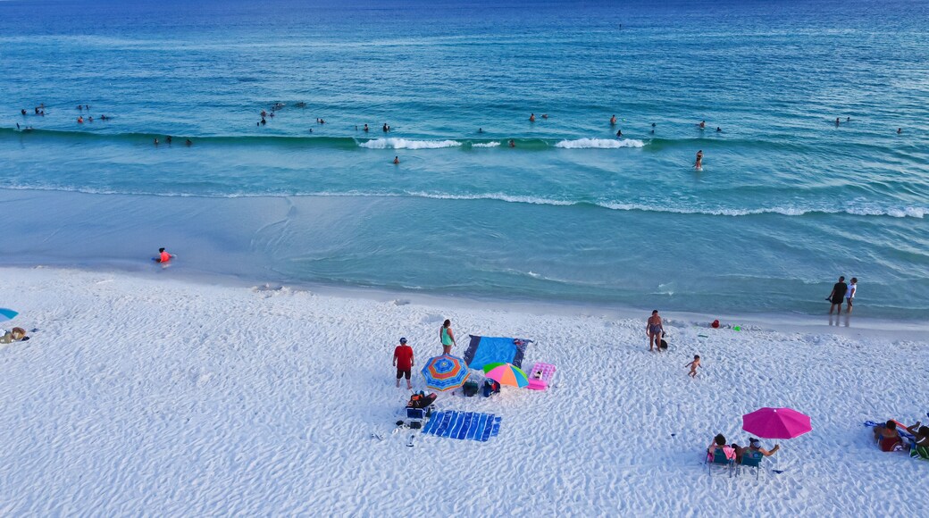Miramar Beach with white sandy shoreline, turquoise water, blue waves and crowded of diverse people swimming, relaxing, colorful tents, canopy, lounge chair, Destin, Florida