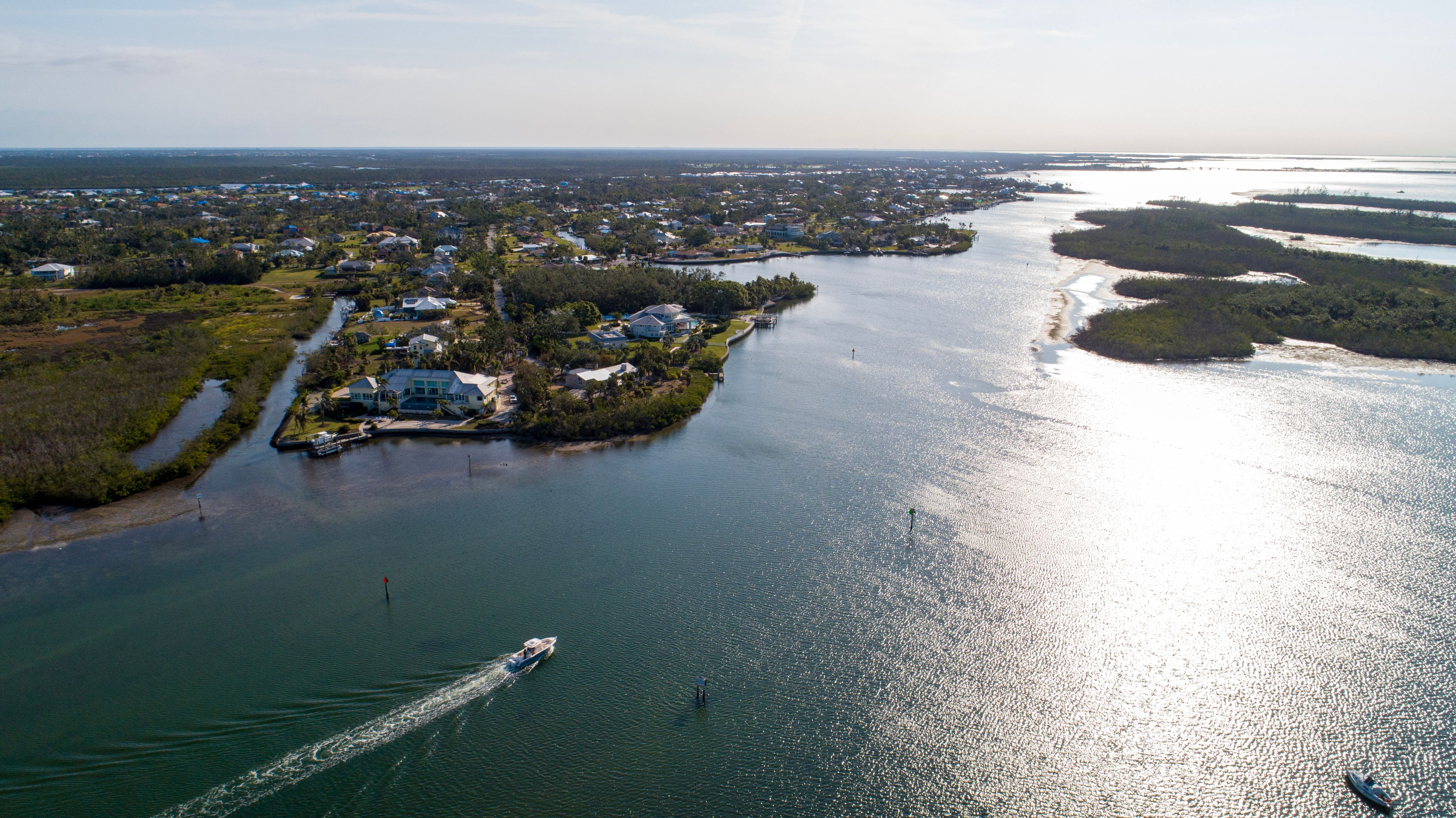 An aerial view of a coastal area with a river, houses, and boats.