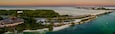 A coastal cityscape with a bridge, marina, and lush greenery.