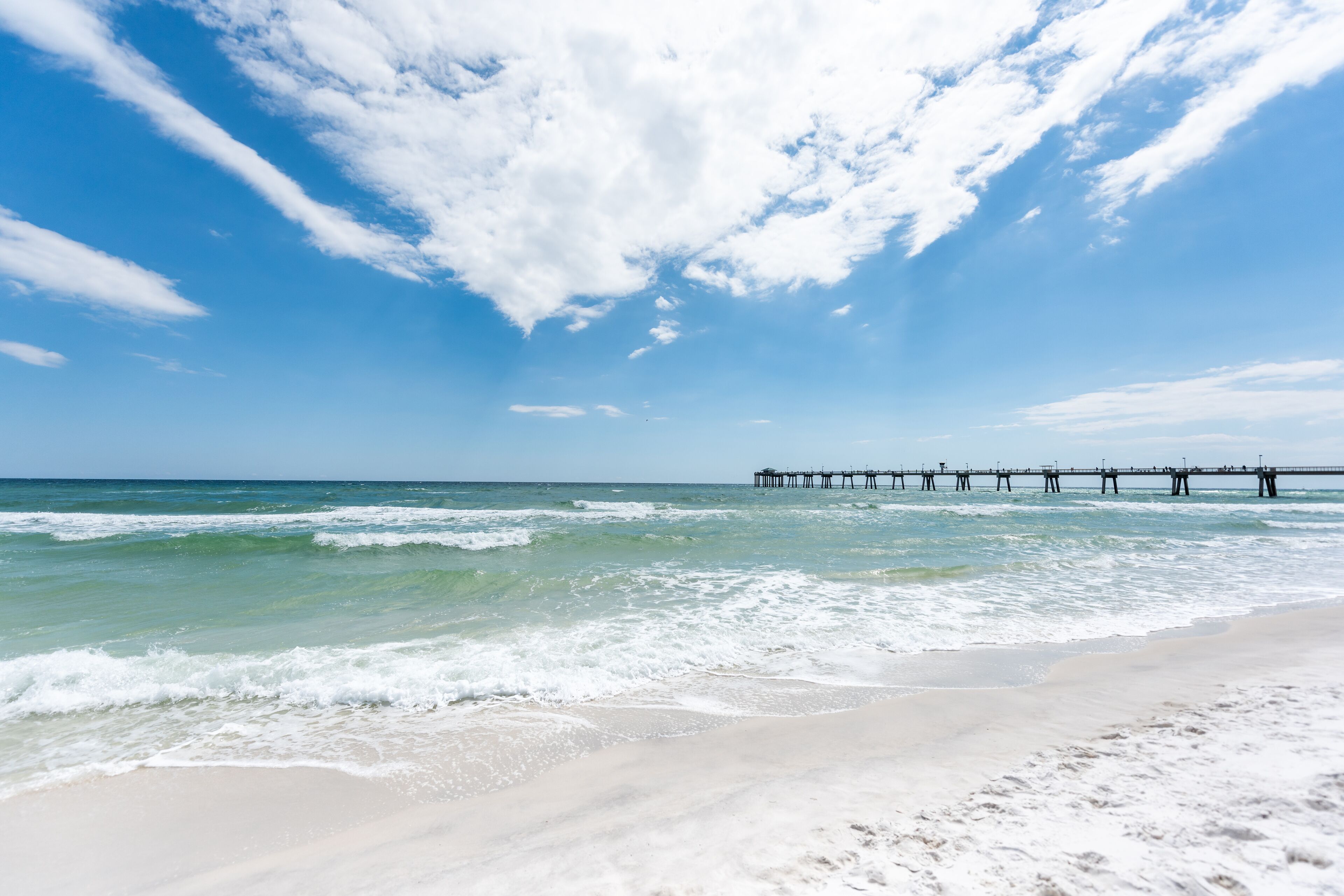 Fort Walton Beach, USA Okaloosa Island fishing pier in Florida in Panhandle, Gulf of Mexico during sunny day, wave crashing on shore, white sand