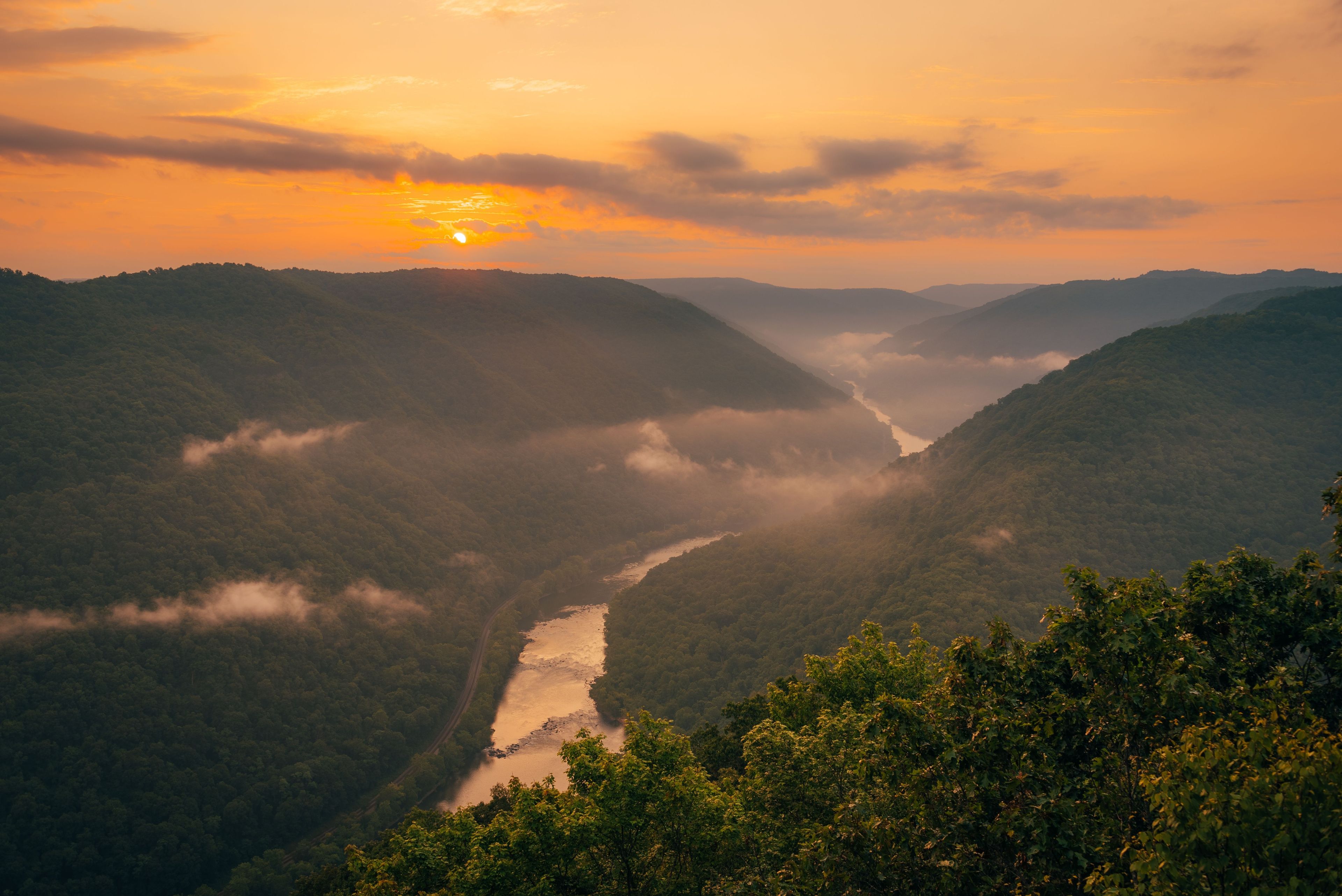 A river winding through a valley with hills on either side, surrounded by dense forest.
