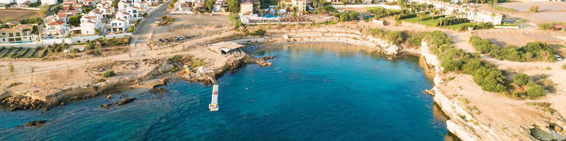 Aerial bird's eye view of Kapparis beach, Protaras, Paralimni, Famagusta, Cyprus. Famous tourist attraction Kaparis bay with boats, sunbeds, restaurant, water sports, people swimming in sea from above