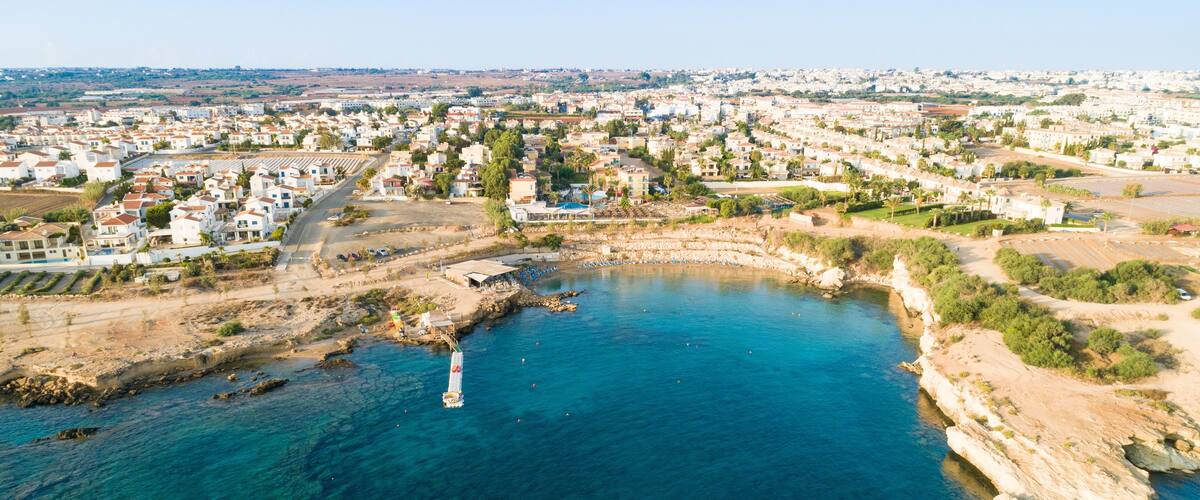 A coastal town with clear blue waters, rocky shores, and residential buildings.