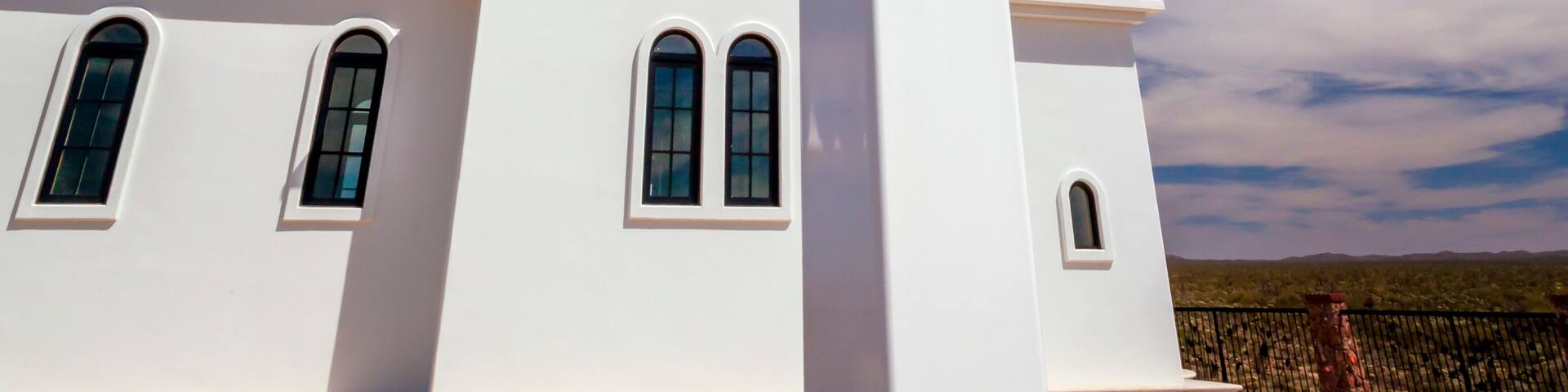 A white church with a blue dome and a cross in front.
