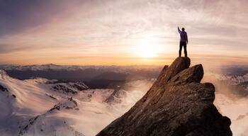 Magical Fantasy Adventure Composite of Man Hiking on top of a rocky mountain peak. Background Landscape from British Columbia, Canada. Sunset or Sunrise Colorful Sky