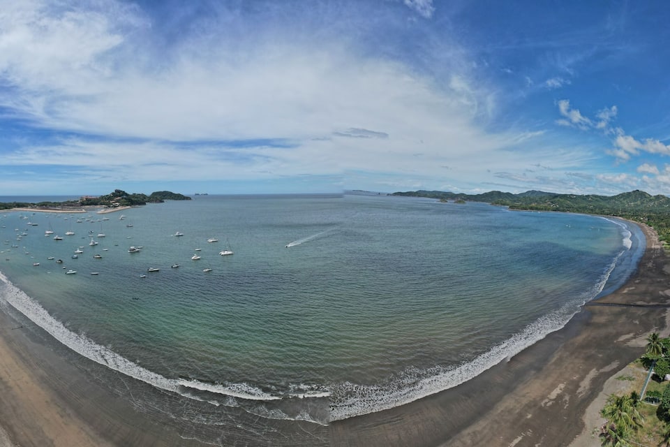 Un paysage côtier avec une plage, des bateaux et des maisons le long du rivage.