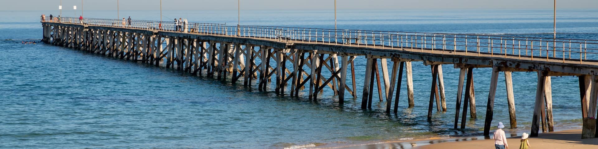 A beach with a wooden pier extending into the ocean.