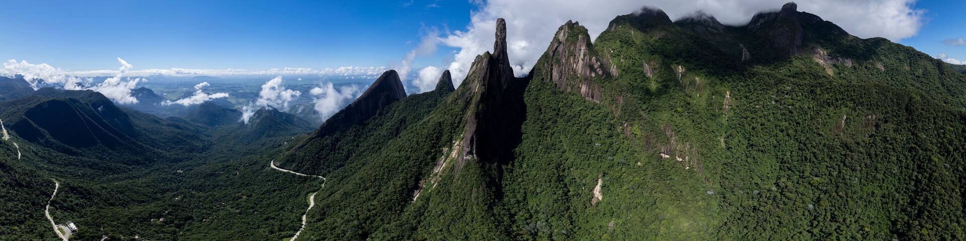 Vibrant wide aerial panorama landscape of mountain range Serra dos Orgaos in Teresopolis, Rio de Janeiro in Brazil with clouds over the rocky peaks. Natural reserve and mountainous Atlantic forest