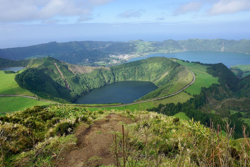 A lake surrounded by green hills and a winding road.