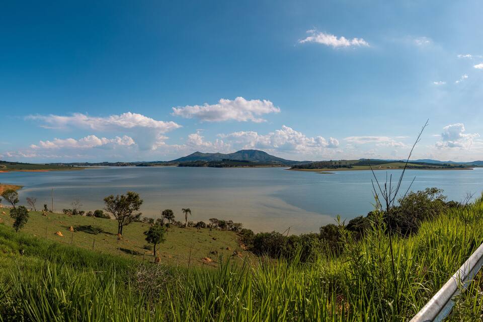 Um lago grande rodeado por colinas e vegetação.