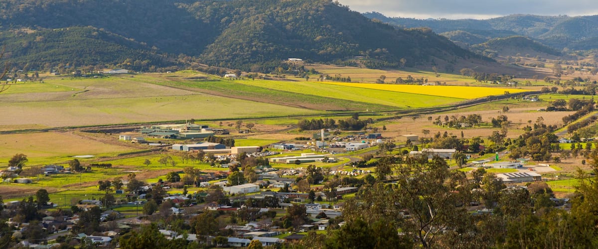 A rural landscape with a town nestled among green fields and hills.