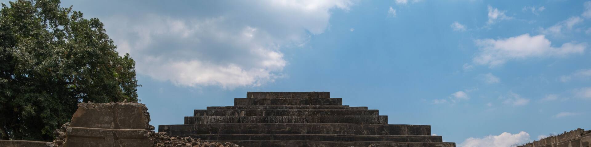 Young man tourist taking photos with the phone at the main pyramid with temple at Tazumal Park archaeological site in El Salvador.