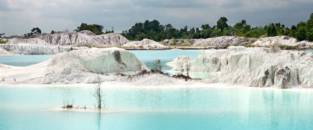 A turquoise lagoon surrounded by white rock formations and sparse vegetation.