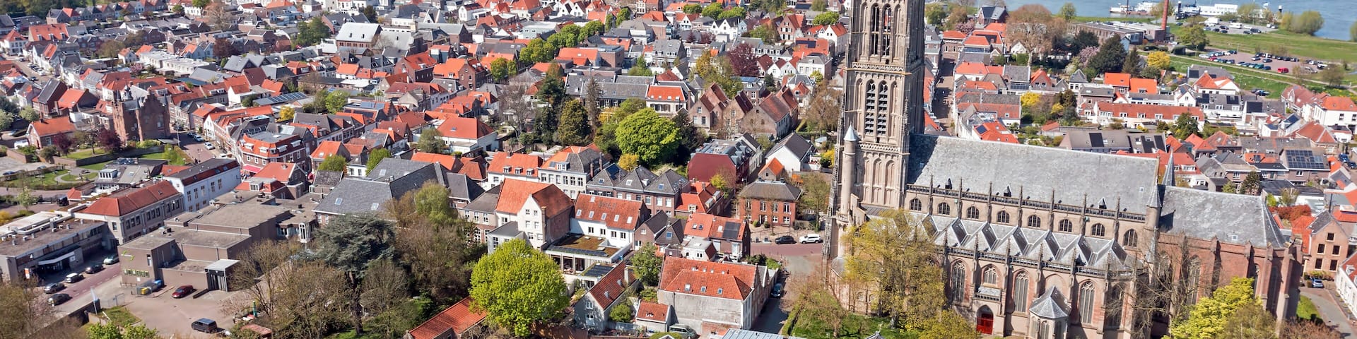 A town with a prominent church, a river, and wind turbines in the distance.