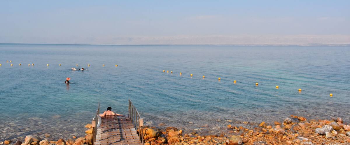 A rocky shoreline with a wooden pier leading into calm waters.