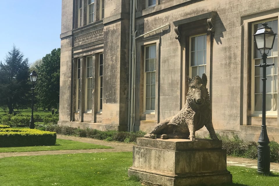 A stone building with large windows and a statue of a dog on a pedestal.