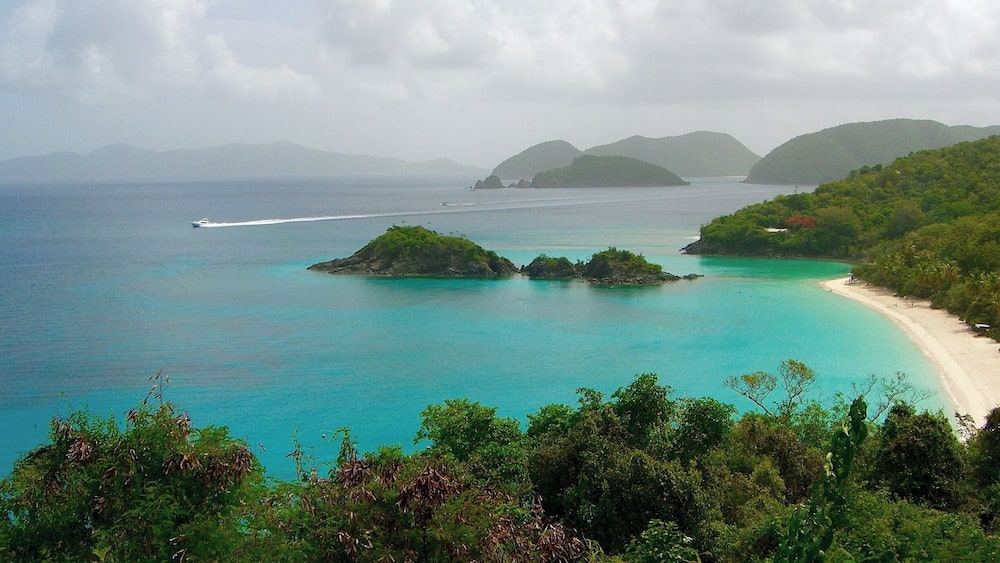 Une plage tropicale aux eaux turquoise, parsemée de petites îles et bordée d’une végétation luxuriante.